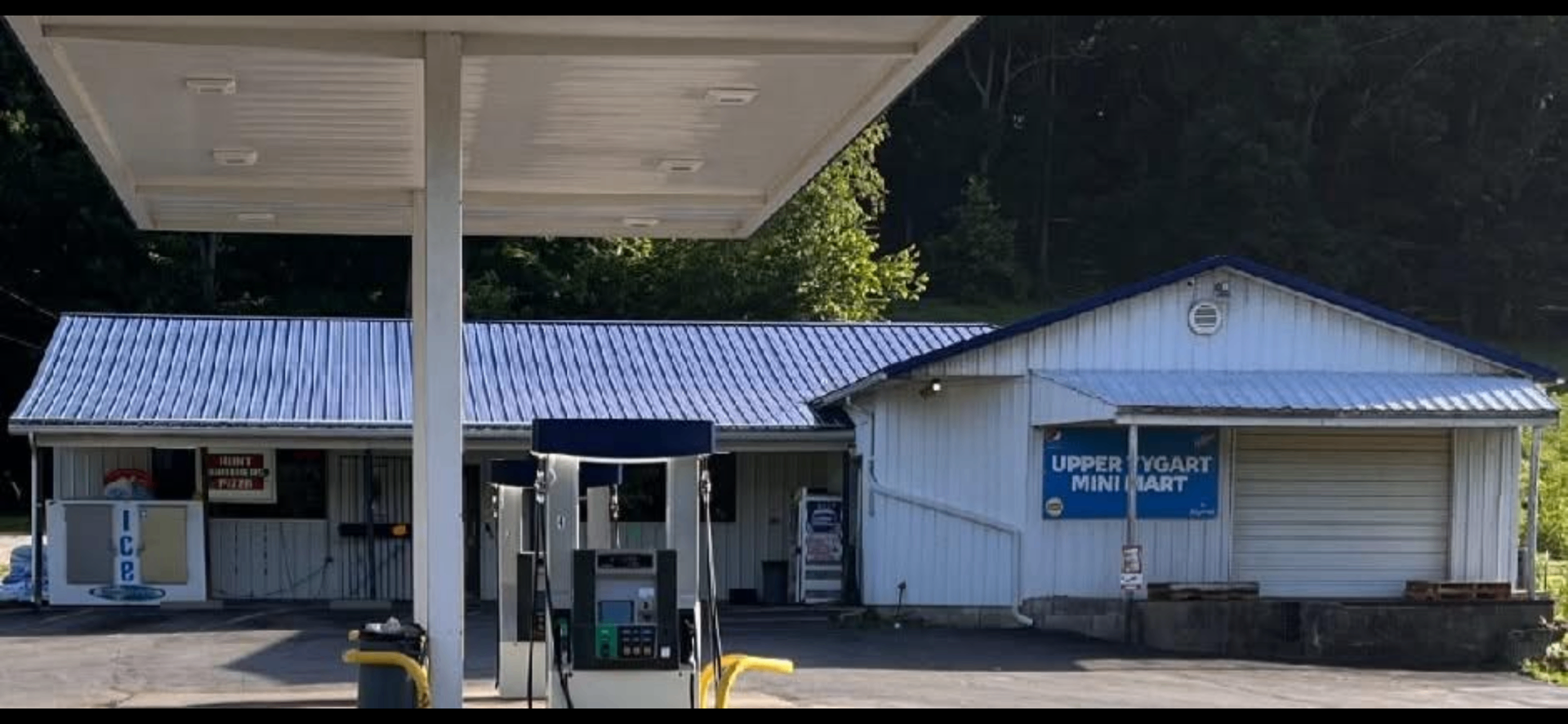 Upper Tygart Mini Mart & Deli store front, gas pumps and Hunt Brothers Pizza sign